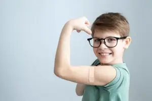 Boy flexing his muscle, smiling after getting his vaccinations